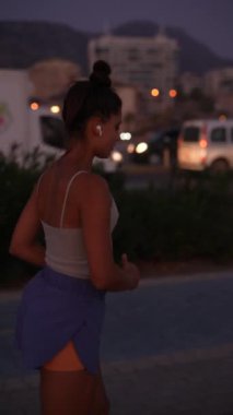 Bir insan alacakaranlıkta koşuyor, canlı bir şehir ortamında sıcak ortam ışıklarıyla aktif olarak zindelik gösteriyor.