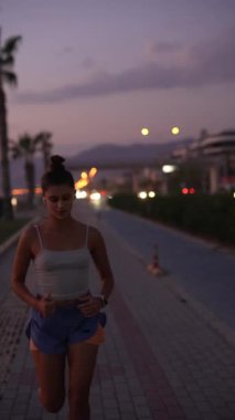 Kendini adamış bir koşucu, canlı palmiye ağaçlarıyla çevrili manzaralı rıhtımda akşam koşusunun keyfini çıkarıyor.