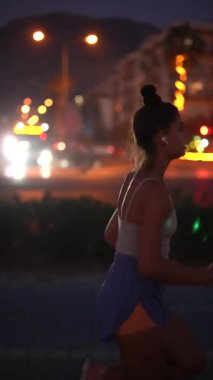 Bir koşucunun çarpıcı silueti enerjik bir şekilde gece canlı, canlı bir şehir ortamında koşuyor.