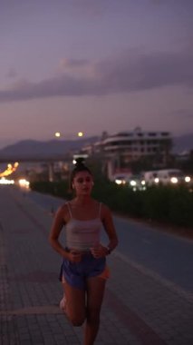 Kararlı bir kadın, gün batımında güzel aydınlatılmış bir şehir yolunda koşar. Hem zindelik hem de derin sükuneti somutlaştırır.