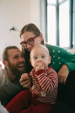 Sevgi dolu bir aile anını yakalıyorum. Sevgi dolu ebeveynler ve onların neşeli bebekleri sıcak, rahat bir ortamda.