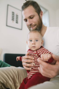 Neşeli ve şefkatli bir baba kıymetli bebeğini sıkıca tutar ve güzel, sıcak bir aile anı yaratır.