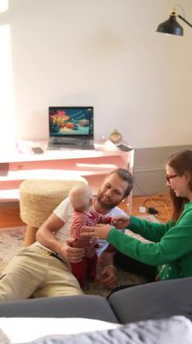 Sıcak ve rahat bir oturma odasında bir bebekle hoş ve neşeli bir aile etkileşimi yaşanıyor.