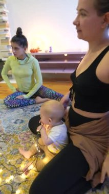 Huzurlu ve huzurlu bir sahnede iki kadın, sıcak ve rahat bir ışığın ortasında bir bebekle huzur içinde meditasyon yapıyorlar.