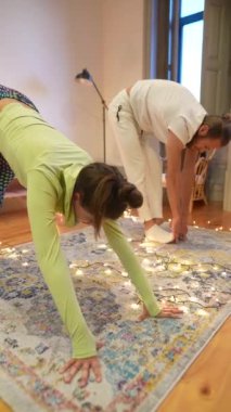 Huzurlu ve huzurlu bir ortamda, rahat peri ışıklarıyla çevrili yoga pratiği yapan iki kişi.