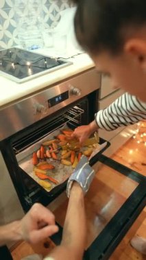 İki yetenekli el, fırından kızarmış sebzelerle dolu sıcak tepsiyi çıkarmaya hazırlanıyor.