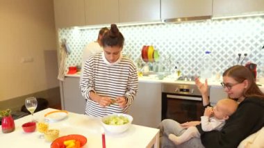 Sıcak ve davetkar bir mutfak sahnesinde aile üyeleri neşeyle takım olarak taze bir salata hazırlıyorlar.