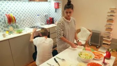 İki insanın neşeyle hazırladığı canlı bir mutfak sahnesi. Taze, canlı malzemelerle lezzetli bir yemek.