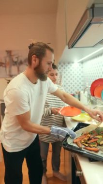 Bir çift şık mutfaklarında birlikte sağlıklı, taze sebzeler hazırlıyor, takım çalışmalarını sergiliyorlar.