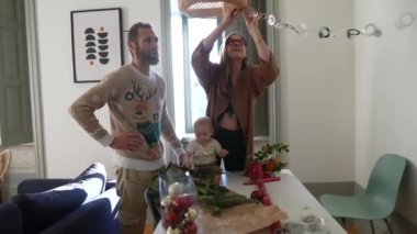 Neşeli bir aile anı, renkli bir kutlama için dekorasyon yaparken kahkahalarla dolu mutlu bir çocukla birlikte.