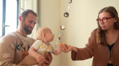 Gerçekten mutlu bir an yakalıyor, bir bebek ve ebeveynlerinin kapalı alandaki eğlenceli etkileşimlerinin keyfini çıkardıkları.