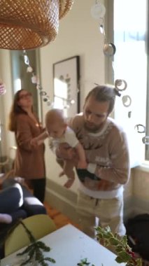 Sevinçli bir ebeveyn değerli bebeğini kucağında tutarken bir başka sevgi dolu aile ferdi de sıcak evlerini dekore ediyor.