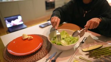 Renkli tabaklar ve taze sebzelerle dolu güzel bir masada bir kişi canlı bir salata yapıyor.