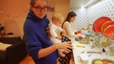 Neşeli bir aile, parlak mutfağında kaliteli zaman geçirir. Bebekleriyle yemek pişirir ve yaratırlar.