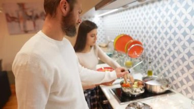 Bir çift, mutfaktaki takım çalışması yeteneklerini sergileyerek, keyifli bir yemek pişirme deneyimini paylaşmayı seviyor.