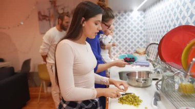 Çağdaş bir mutfakta birlikte yemek hazırlama sanatıyla uğraşan üç birey aile bağlarını güçlendiriyor.