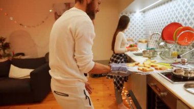 Neşeli bir çift, sıcak ve hoş bir mutfak ortamında lezzetli ve lezzetli yemekler hazırlıyor.