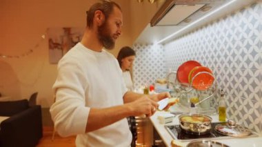 Neşeli bir çift, modern bir mutfakta lezzetli yemekler pişirir. Yaratıcılık ve neşe dolu bir anı paylaşırlar.