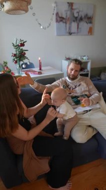 Sıcak ve samimi bir aile anı. Bir bebeğin oyun sırasında hem anne hem de babasıyla neşe içinde etkileşime girdiği.