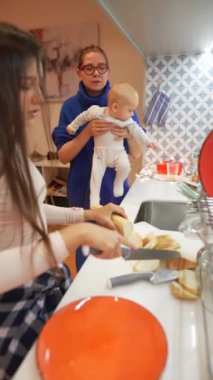 Neşeli bir mutfakta leziz yemekler pişirirken aile bağlarının sıcak bir sahnesi huzur ve mutluluk saçıyor.