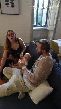 Neşeli bir aile anı canlı bir oturma odasında, sevimli bir bebek ve sevgi dolu bir ebeveynin yer aldığı görüntülenir.