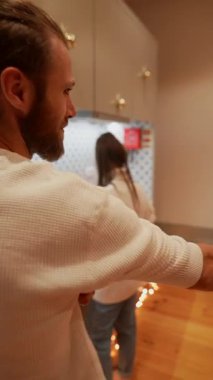 Sıcak bir mutfak sahnesinde, bir adam neşe içinde neşeli ve eğlenceli bir saç stiliyle eğlenirken mutlu bir şekilde yemek pişirir.