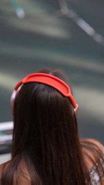 Uzun dalgalı saçlı genç bir kadın şık kırmızı kulaklıklarını takıp müzik dinlemekten hoşlanıyor.