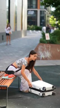 Canlı bir şehir ortamında neşeli bir ruhu olan genç bir kız ilginç bir şekilde macera dolu bavulunu inceliyor.