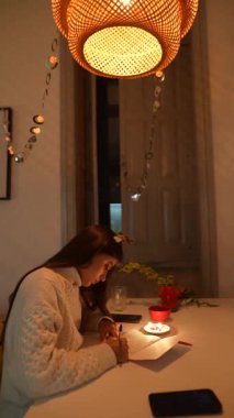 Huzurlu ve huzurlu bir an, mum ışığında yazarak, samimi ve davetkar bir ortamla çevrili.