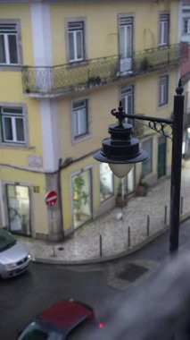 Lizbon 'daki büyüleyici bir sokak sahnesinde sokak boyunca klasik bir lamba direği ve renkli binalar yer alıyor.