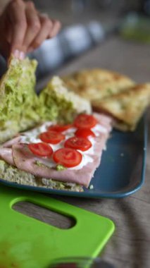 Lezzetli bir jambonlu sandviç yapıyorum olgun domatesler ve kremalı dolgu, leziz bir mutfak anını vurguluyorum.