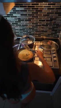 Bir insan, çeşitli tencere ve tavalarla dolu parlak ve modern bir mutfakta ustalıkla ve ustalıkla lezzetli yemekler pişirir.