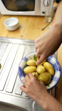 Modern, şık bir mutfak ortamında taze patatesleri ustalıkla dilimleyen ellerin yakın çekimi.