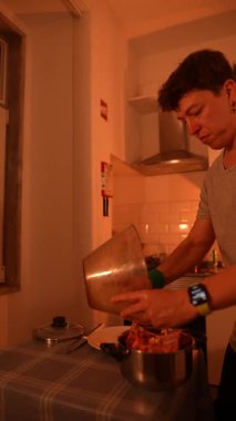 Bir insan sıcak bir mutfakta ustalıkla yemek hazırlar. Mutfak yaratıcılığını ve ev yemeğini gösterir..