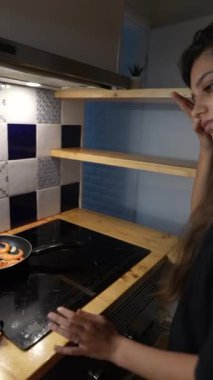 Güzel tasarlanmış ve şık bir mutfakta, genç bir kadın ustalıkla ve tutkuyla çeşitli yemekler pişirir.