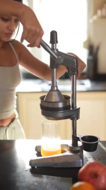 Parlak bir mutfakta, bir birey taze meyvelerden meyve suyu elde etmek için ustalıkla elle narenciye ezici kullanır.