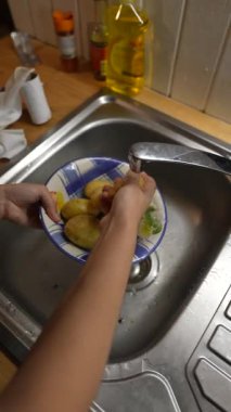Yemek hazırlamak amacıyla mutfak lavabosunda taze patates yıkamak için pratik bir yaklaşım.