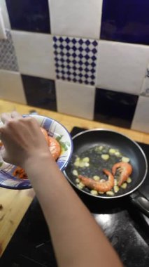 Becerikli bir şef, işlevsel bir mutfakta sarımsak, ot ve baharatla enfes bir karides yemeği hazırlar.