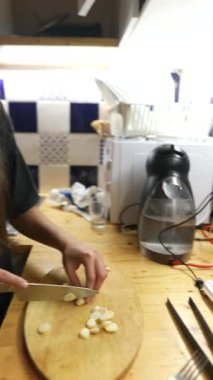 Genç bir kadın zarif bir şekilde tasarlanmış ahşap kesme tahtasıyla sarımsak doğruyor.