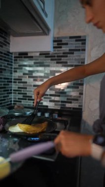 Modern, şık bir mutfakta omlet çevirmekte usta bir birey çağdaş dekorasyonla süslenmiş.