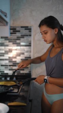 Genç bir kadın, yemek pişirme yeteneğini sergileyerek, modern mutfağında lezzetli bir yemek hazırlıyor.