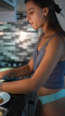 Genç bir kadın, modern bir mutfakta zevkle yemek pişirir. Mutfak becerilerini ve yaratıcılığını göstererek.