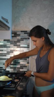 Genç bir kadın şık bir mutfakta, modern mutfak tekniklerini sergileyerek ustaca kahvaltı hazırlıyor..