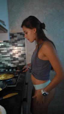 Aşçılık yeteneğini sergileyen genç bir kadın şık bir mutfakta ustalıkla yemek pişiriyor.