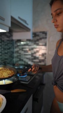 Genç bir kadın şık mutfağında ustalıkla krep yapıyor, aşçılık uzmanlığını ve tutkusunu sergiliyor.