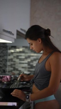 Genç bir kadın şık bir mutfakta leziz bir yemek karıştırıyor, aşçılık becerilerini ve adanmışlığını gösteriyor.