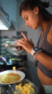 Şık ve modern bir mutfakta, genç bir kadın canlı malzemeler kullanarak lezzetli krepleri ustalıkla hazırlar.