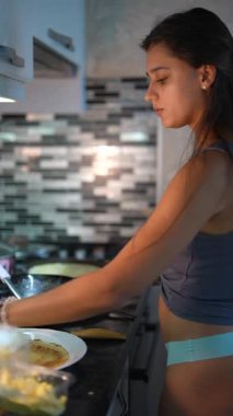 Tutkulu genç bir kadın mutfağında leziz bir yemek hazırlıyor ve mutfak yeteneklerini gösteriyor.