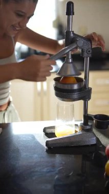 Bir kadın şık ve modern mutfak alanında manuel meyve sıkacağı kullanarak ustalıkla taze meyve suyu yapar.