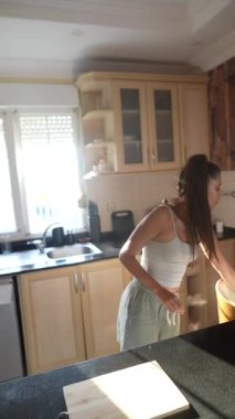 Genç bir kadın, sağlıklı beslenmenin önemini vurgulayarak modern mutfağında taze meyve hazırlıyor.